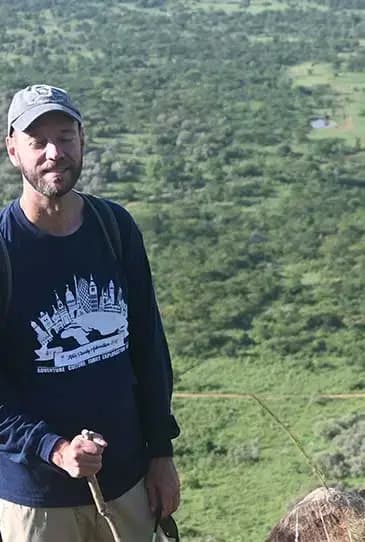 Guest on a guided nature walk, green Mara hills and woodland behind